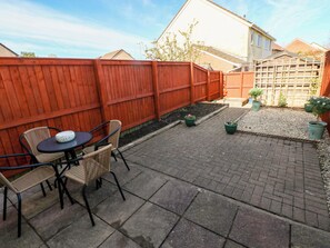 A patio with a table and chairs, a red fence, and potted plants. - The Gower Gateway (Swansea)