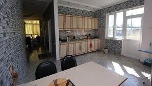 A kitchen with a stone backsplash, wooden cabinets, a dining table, and a window with a view.
