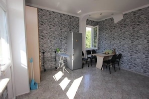 A compact kitchen with a refrigerator, a dining table with chairs, and a window providing natural light.
