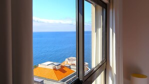 Ein Fenster mit Blick auf das Meer und ein Gebäude mit orangen Dächern.