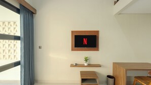Una camera moderna con una scrivania in legno, una piccola panca, una pianta e il logo Netflix sul muro.