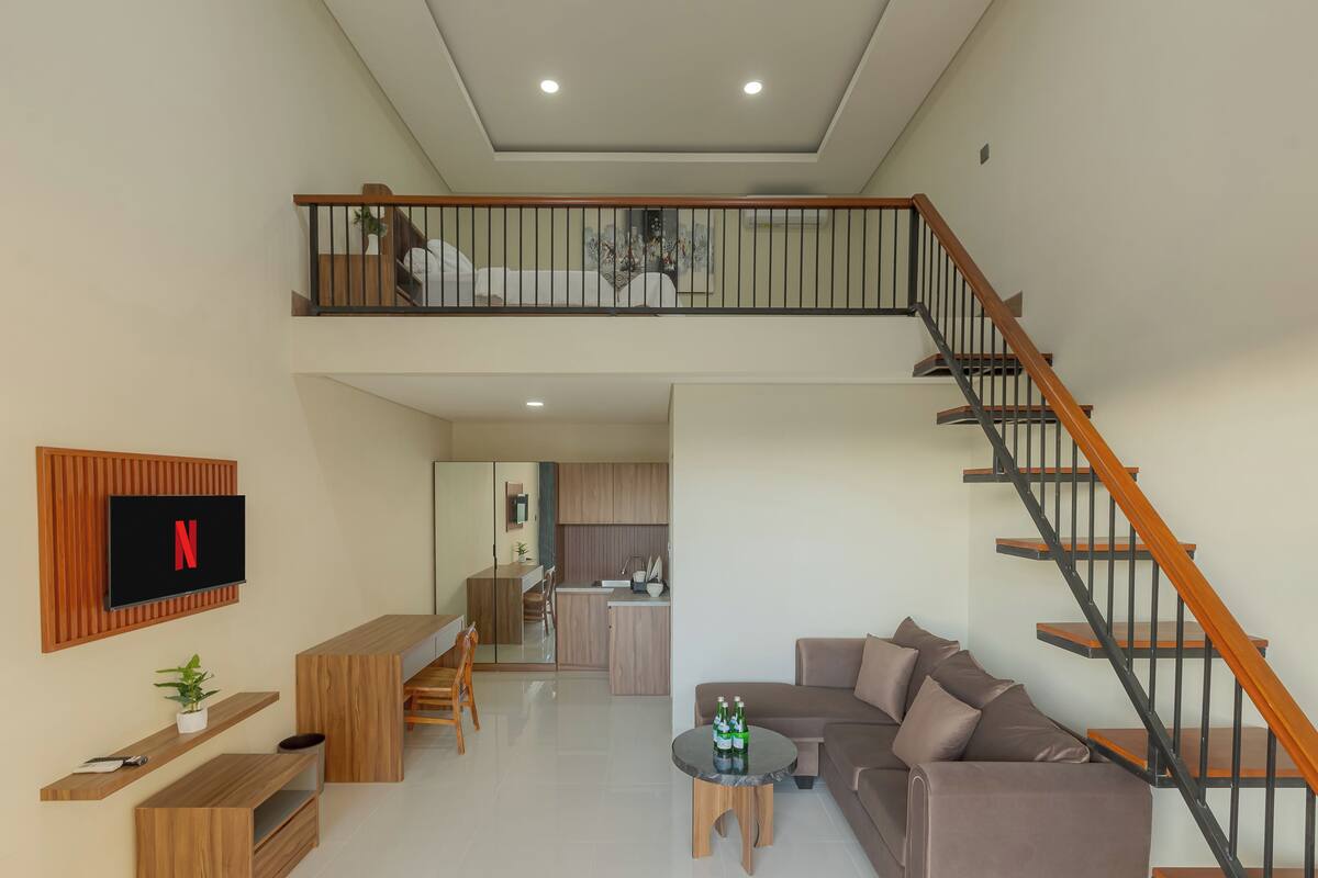 A modern apartment with a living room, dining area, kitchen, and a staircase.