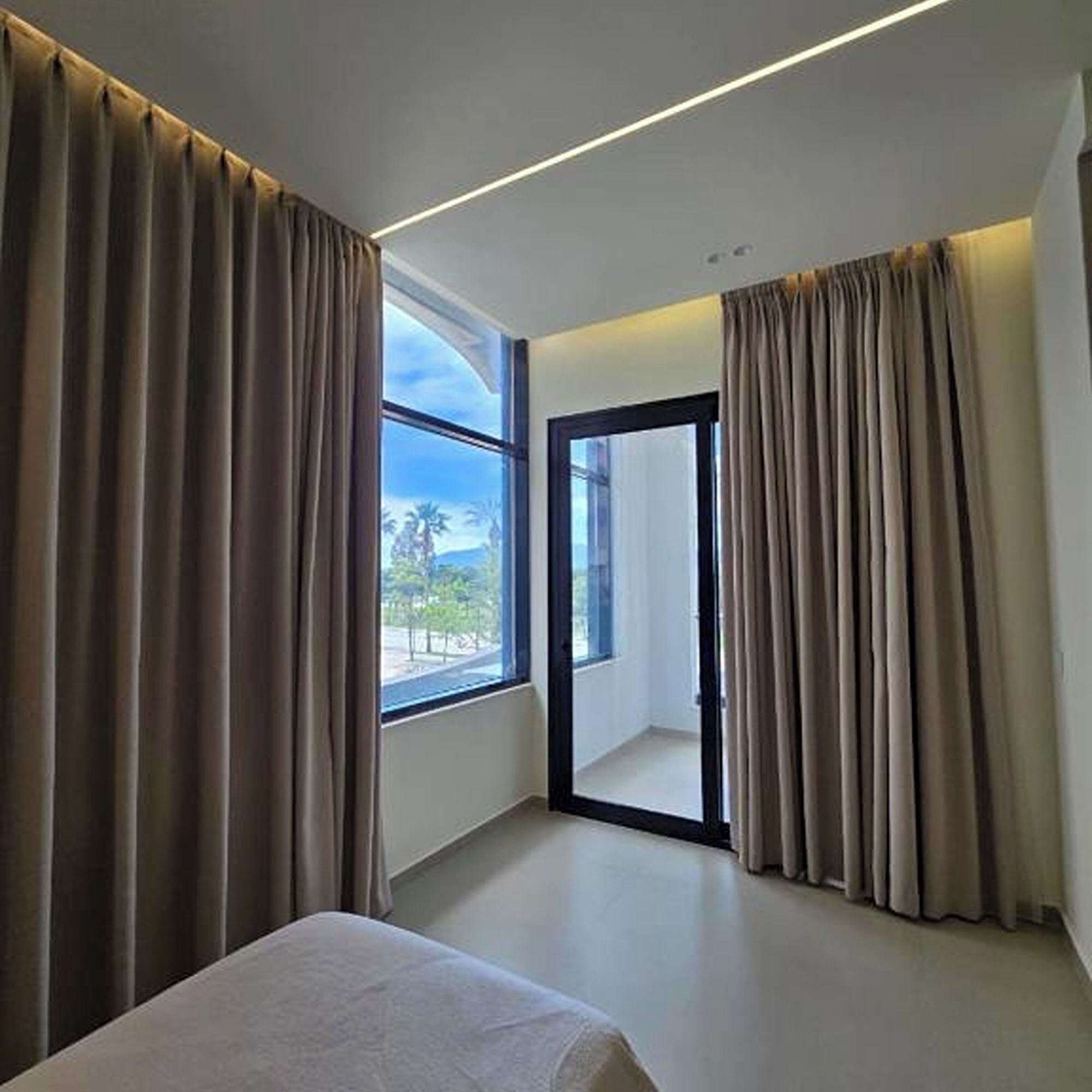 Une chambre d’hôtel avec un lit, une grande fenêtre et une porte donnant sur l’extérieur.