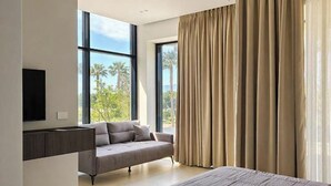 A modern bedroom with a large bed, a sofa, and a TV mounted on the wall. - Suites By Jordan's Hotel (Vlore)