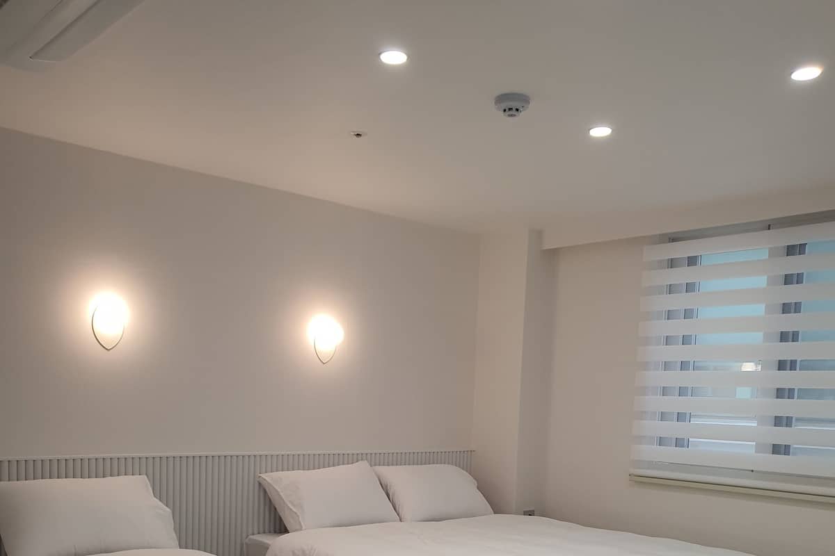 Una camera da letto con due letti, una finestra con persiane e luci a parete.