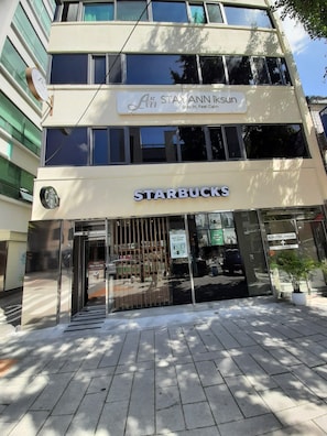 A two-story building with a Starbucks entrance, a sign above the entrance, and a potted plant outside. - STAY Ann Iksun (Seoul)