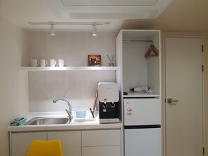 Una cocina compacta con un lavamanos, una cafetera y un refrigerador.