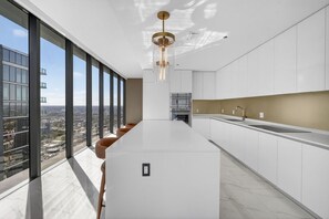 Eine moderne Küche mit einer großen Kochinsel, Blick auf die Stadt und einer außergewöhnlichen Pendelleuchte.