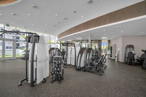 Ein modernes Fitnessstudio mit verschiedenen Trainingsgeräten, einer gewölbten Decke und großen Fenstern.
