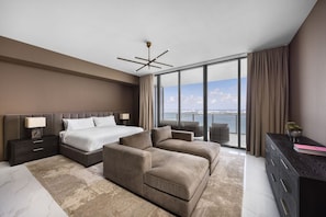 Une chambre moderne avec un grand lit, un canapé, un bureau et une vue sur la mer.