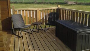 Een houten terras met twee stoelen en een jacuzzi.