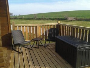 A wooden deck with two chairs and a hot tub.