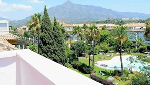 Un resort con piscina, palmeras y una montaña al fondo.