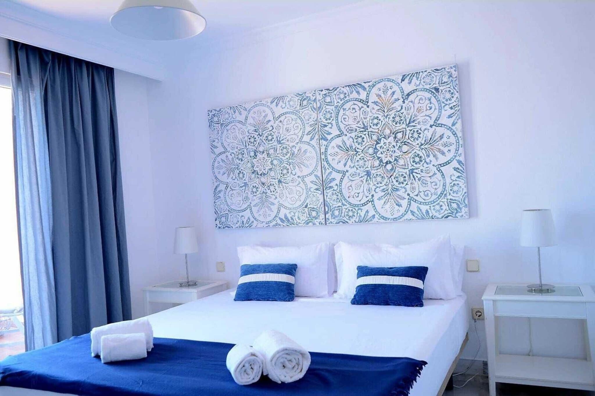 Ett hotellrum med en säng, två sängbord, en stor väggbonad med blommönster och utsikt över omgivningarna.