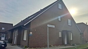 A two-story brick building with a sign reading 'Schwalbennest.' - Ferienwohnung fur 4 Personen in Nessmersiel (Dornum)