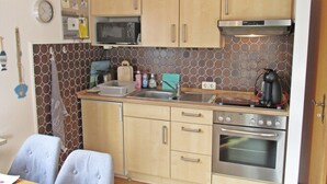 A compact kitchen with a microwave, toaster, sink, and oven. - Ferienwohnung fur 4 Personen in Nessmersiel (Dornum)