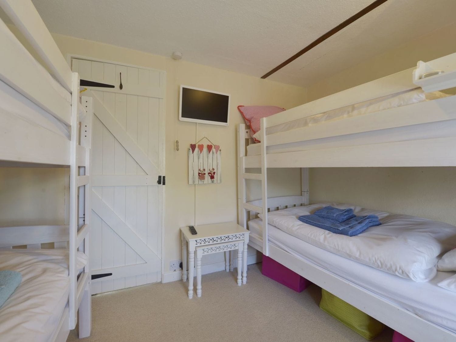 A bunk bed room with a door, a small table, and a wall decoration.