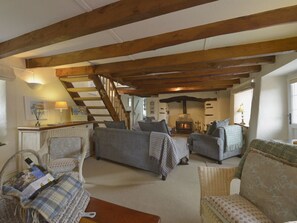 Ein gemütliches Wohnzimmer mit Kamin, Holzbalken und bequemen Sitzgelegenheiten.