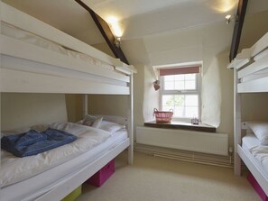 Une chambre avec un lit superposé, une fenêtre, un radiateur et un panier posé sur le rebord de la fenêtre.
