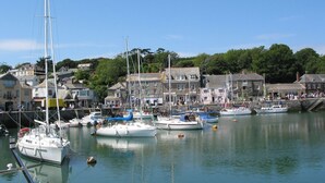 A harbor with boats docked, buildings along the waterfront, and a clear sky. - Mays Cottage (Wadebridge)