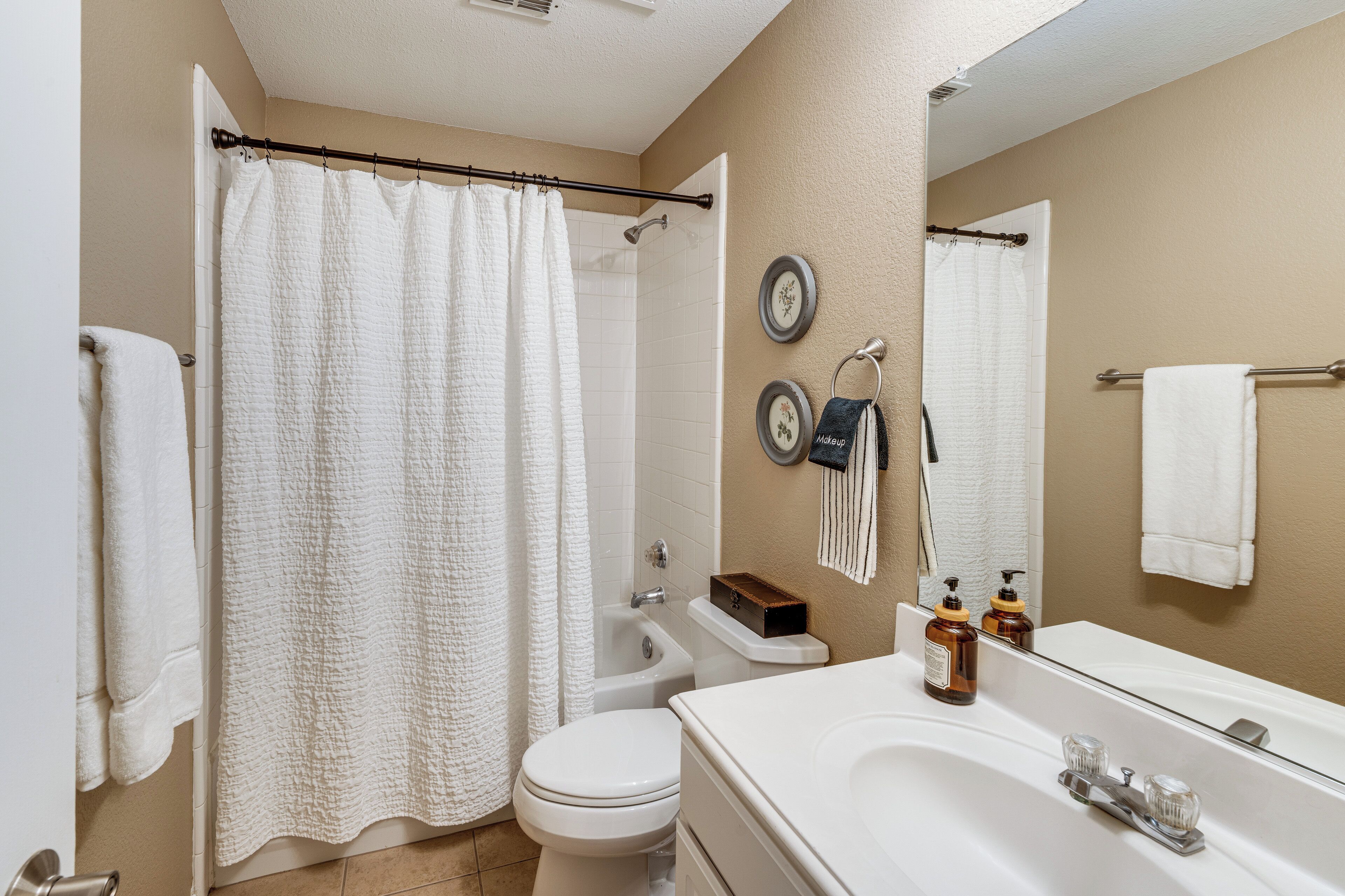 A bathroom with a shower curtain, toilet, sink, and a mirror.