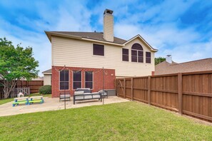 A two-story house with a backyard patio, a wooden fence, and a chimney. - 4 Mi to Toyota Stadium! Spacious Frisco Retreat (Frisco)