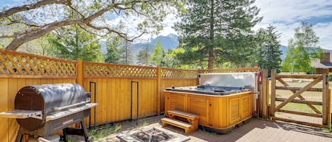 Een achtertuin met een barbecue, een hottub en zitplaatsen buiten.