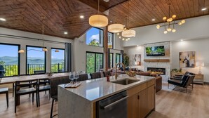 Un'ampia cucina con un'isola grande, soffitto in legno e ampie finestre che offrono vista sull'esterno.