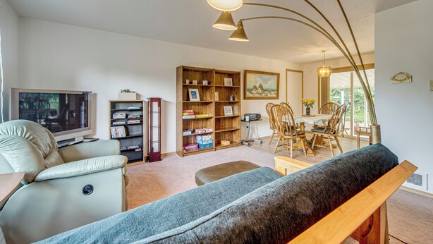 A living room with a television, bookshelves, a sofa, and a dining area with chairs. - Ocean City Home w/ Fenced Yard: 1 Mi to Beach! (Ocean Shores)