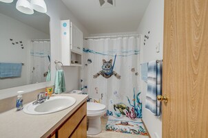 Un baño con lavamanos, inodoro y cortina de ducha con diseño de vida marina.