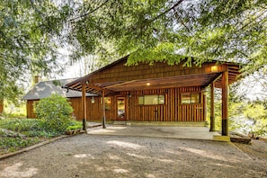 A wooden cabin with a covered porch, a gravel driveway, and a well-maintained garden.