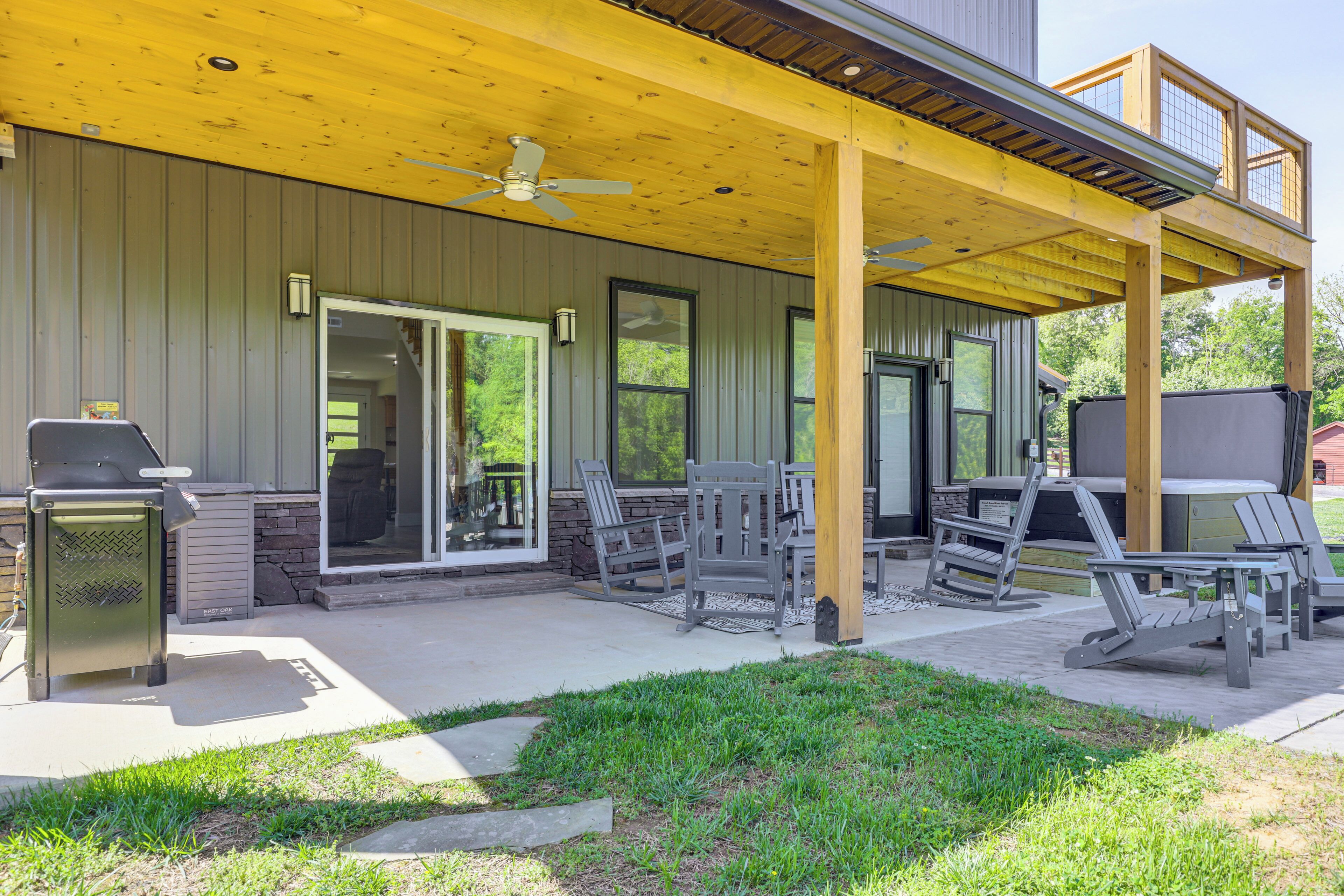 A covered patio with outdoor seating, a grill, and a ceiling fan.
