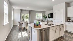 A modern kitchen with a central island, white cabinetry, and a dining area with a table and chairs. - Family-friendly Cape May Retreat Near the Beach (Cape May)