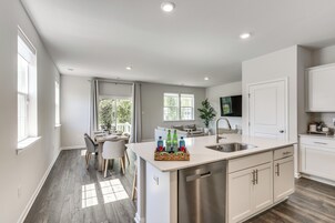 A modern kitchen with a central island, white cabinetry, and a dining area with a table and chairs.