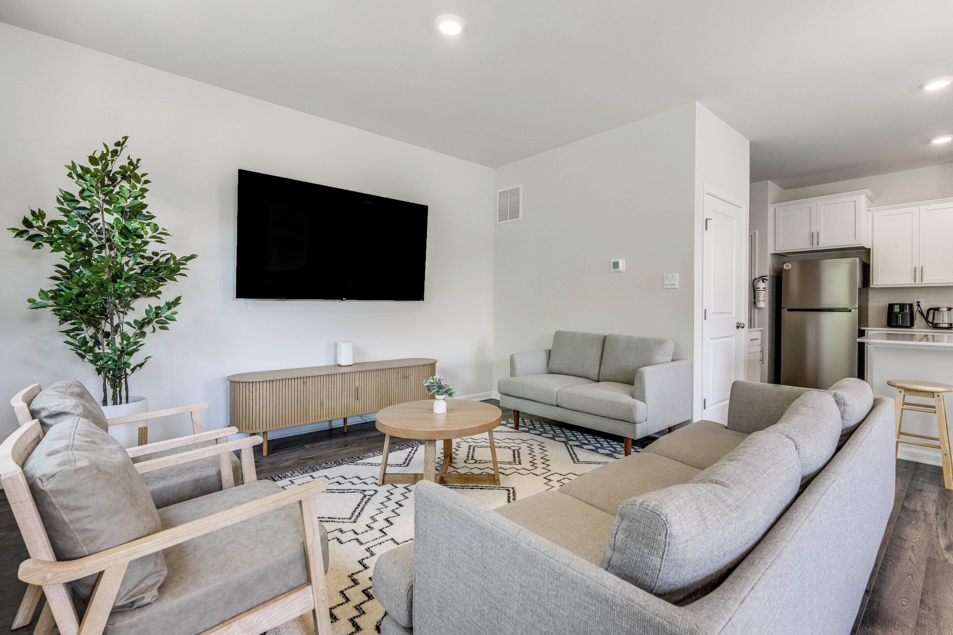 Een moderne woonkamer met een bank, fauteuil, salontafel en een flatscreen televisie.