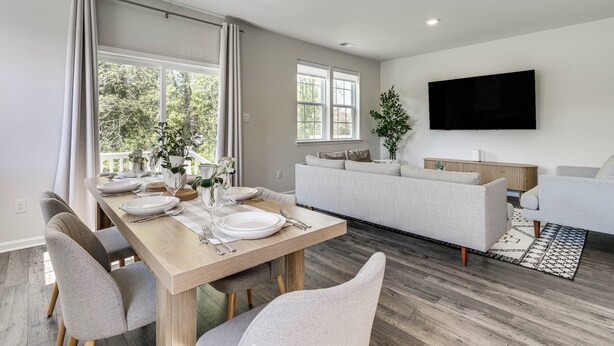 A modern living room with a sofa, a dining table set for four, and a flat-screen TV mounted on the wall. - Family-friendly Cape May Retreat Near the Beach (Cape May)