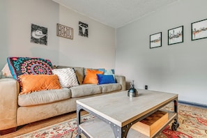 Ein Wohnzimmer mit einer Couch, bunten Kissen, einem Couchtisch und Wandbildern.