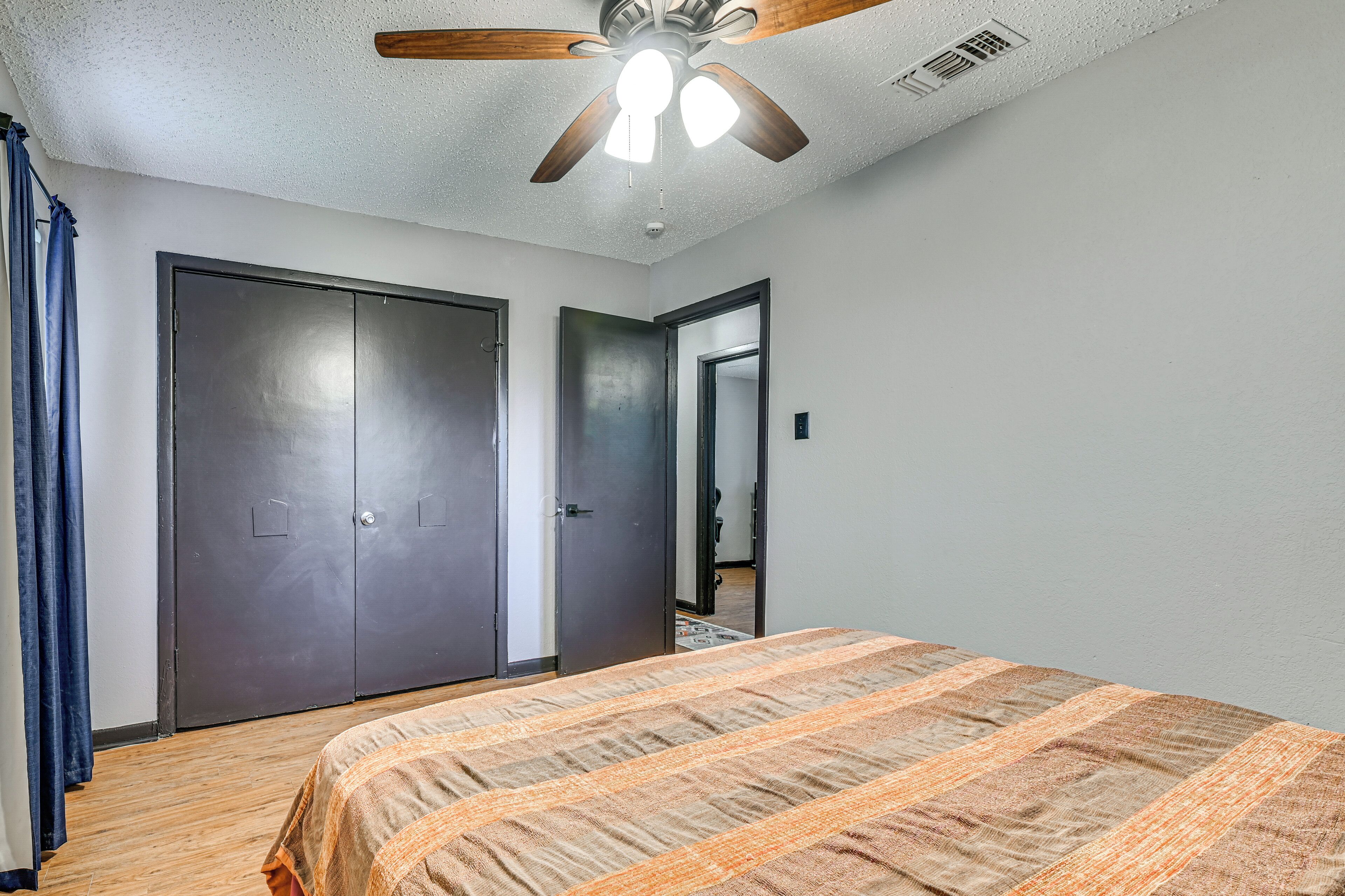 A bedroom with a bed, a ceiling fan, and a wardrobe.