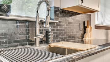 A kitchen with a modern faucet, a wooden cutting board, and a potted plant.