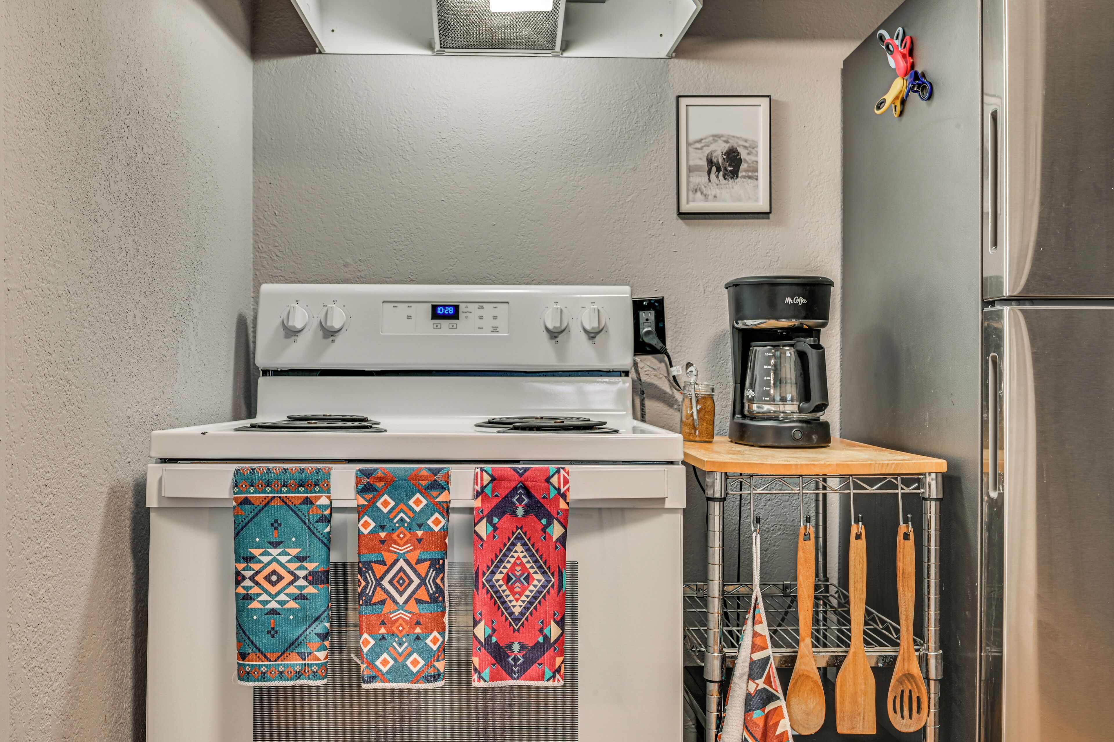 A kitchen with a white stove, a coffee maker, and wooden utensils hanging on a rack.