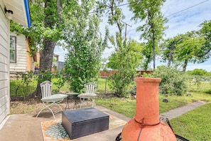 Eine Terrasse mit Gartenmöbeln, einer großen Vase und einem Baum.