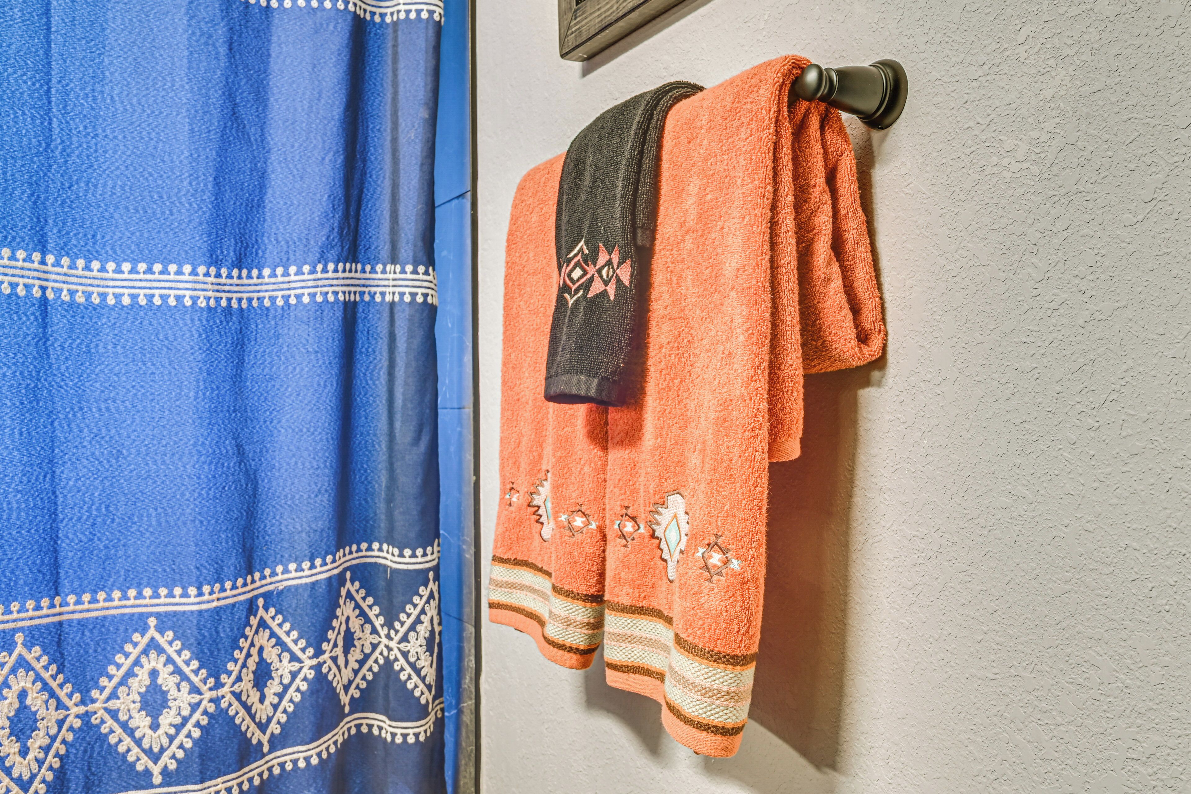 Une salle de bain avec une serviette bleue et une serviette orange suspendues à un porte-serviettes fixé au mur.