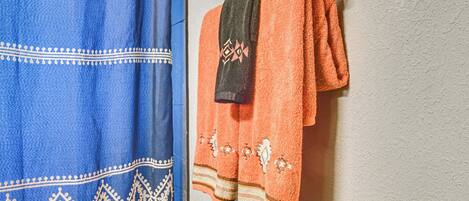 Une salle de bain avec une serviette bleue et une serviette orange suspendues à un porte-serviettes fixé au mur.