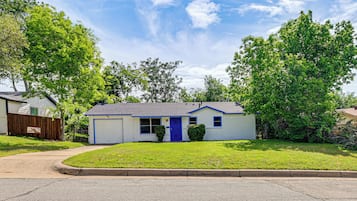 A single-story house with a blue door, a garage, and a well-maintained lawn.