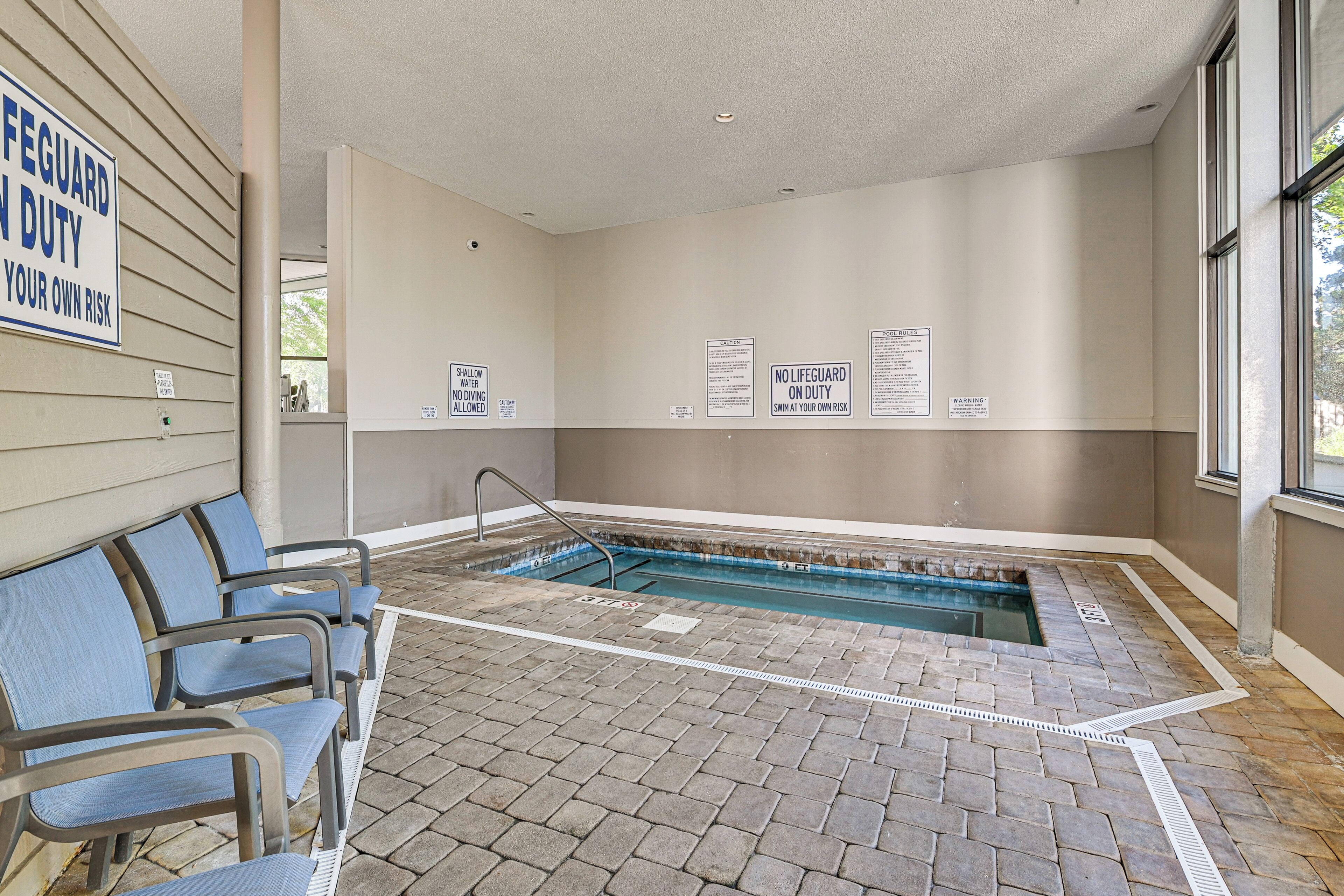 A pool area with a lifeguard duty sign, a shallow water warning sign, and a no lifeguard on duty sign.
