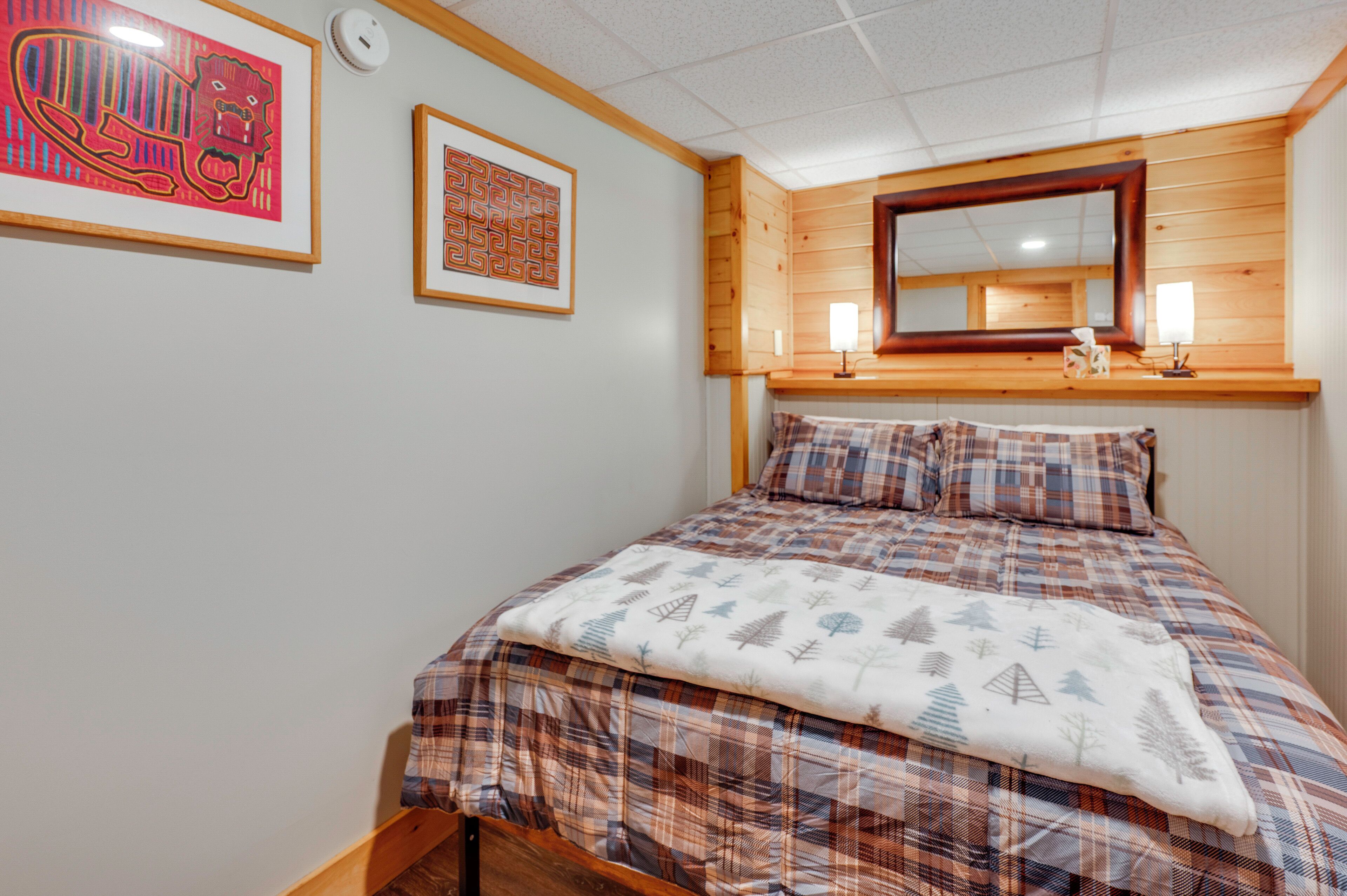 Un dormitorio con una cama, cabecera de madera, un espejo y dos cuadros en la pared.