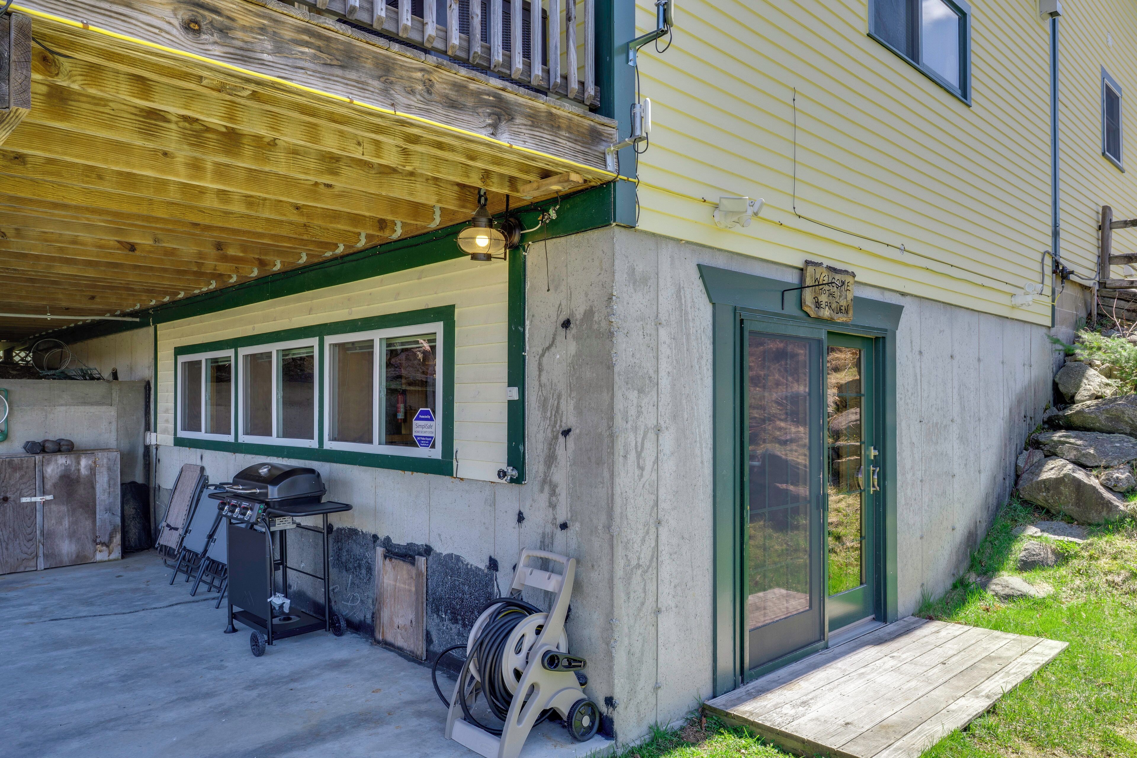A building with a covered patio, a grill, and a door with a sign.