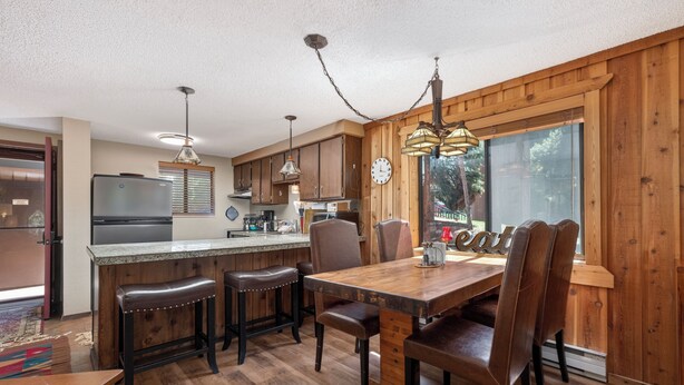 A kitchen with wooden cabinets, a refrigerator, a dining table with chairs, and a bar area. - Beaver Village Unit #0611 Renovated ground floor family unit clubhouse amenities (Winter Park)