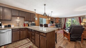A kitchen with wooden cabinets, a granite countertop, and a dining area with a chair and table. - Beaver Village Unit #0611 Renovated ground floor family unit clubhouse amenities (Winter Park)
