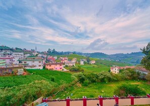 A rural landscape with houses, greenery, and a clear sky. - Ooty Blossom Retreat by VOYE HOMES (Ooty)